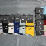 نمایش طیف گسترده رنگی جوراب‌های نیم ساق نایکی با لوگوی کلاسیک Swoosh روی زمینه خاکستری