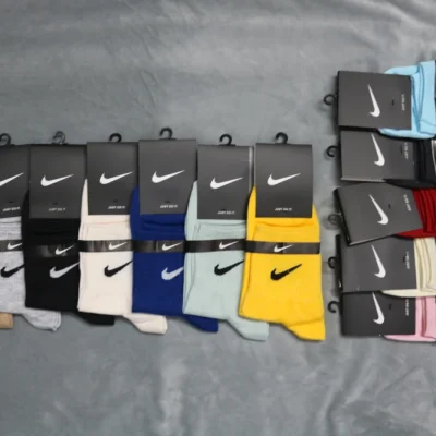 نمایش طیف گسترده رنگی جوراب‌های نیم ساق نایکی با لوگوی کلاسیک Swoosh روی زمینه خاکستری